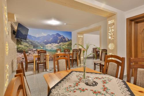 a dining room with a table and chairs and a painting on the wall at Agroturystyka Pokoje na Zakręcie in Białka Tatrzańska