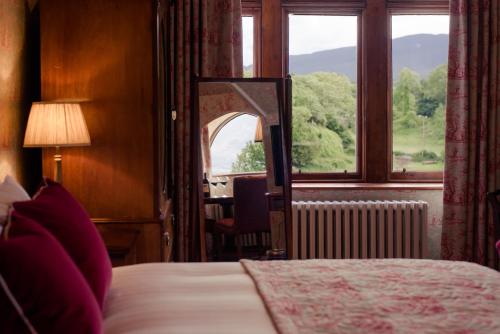 a bedroom with a bed and a mirror and a window at Cahernane House Hotel in Killarney