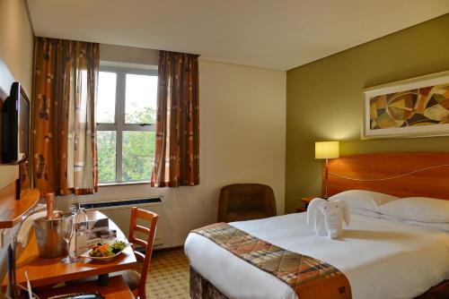 a hotel room with a bed and a table and a desk at Road Lodge Sandton in Johannesburg