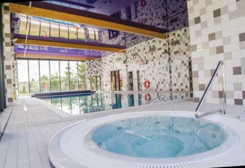 a large jacuzzi tub in a building with a pool at Apartament TOP Pięć Mórz basen&SPA in Sianozety