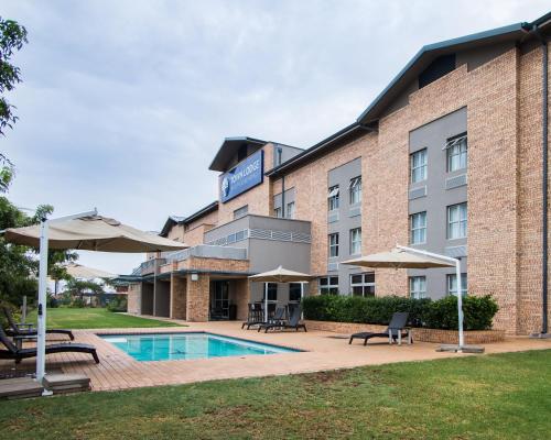 um hotel com piscina, cadeiras e guarda-sóis em Town Lodge Gaborone em Gaborone