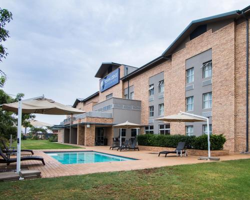 a hotel with a pool and chairs and umbrellas at Town Lodge Gaborone in Gaborone