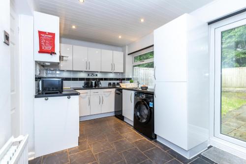 a kitchen with white cabinets and a washer and dryer at CAPRI 13 SA - 3 Bedroom House close to Loughborough University, EV car facilities, Free Parking, Free Wifi - Ask for contractor rates! in Loughborough
