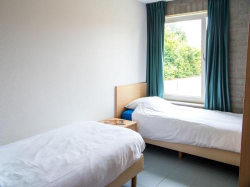 two beds in a room with a window at Vakantiepark Broedershoek in Koudekerke