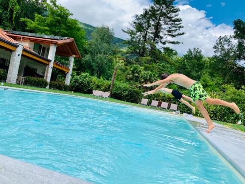 a young man jumping into a swimming pool at House & Pool in Mergozzo