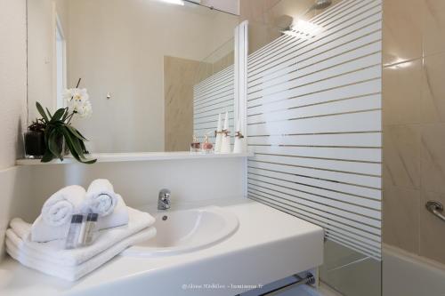 a white bathroom with a sink and a mirror at Résidence New Rochelle in La Rochelle