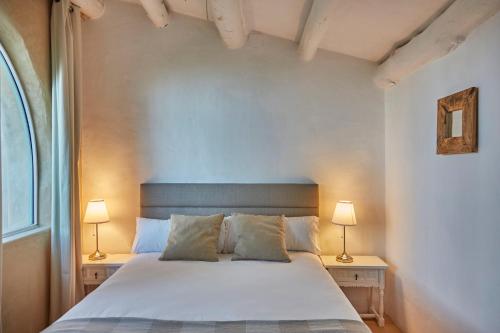 a bedroom with a white bed with two lamps at Casa Los Arcos at Masia Nur Sitges, Adults only in Canyelles