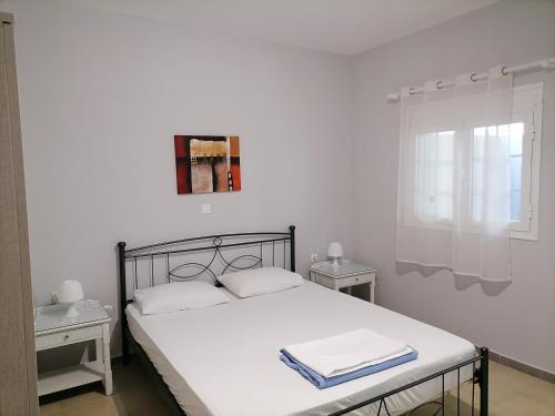 a bedroom with a bed with white sheets and a window at Johny Clara Apartment in Kos