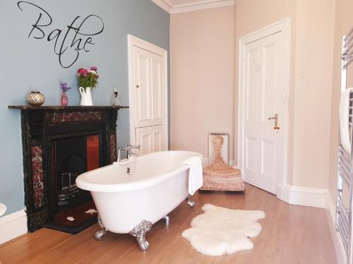 a white bath tub in a bathroom with a fireplace at Old Farm Holiday Cottages - Scottish Borders in Chirnside