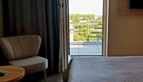 a bedroom with a bed and a chair and a window at Hotel Clement in Prague