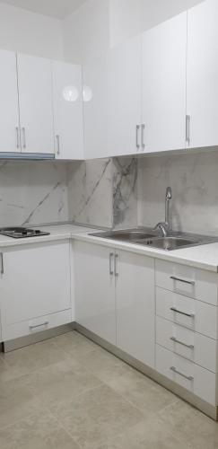 Una cocina blanca con gabinetes blancos y un fregadero. en Redsun Apartment, en Vlorë