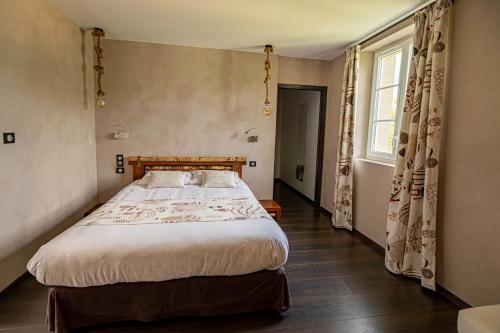 a bedroom with a large bed and a window at Château de la Falque, The Originals Relais in Saint-Geniez-dʼOlt