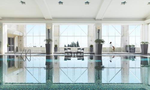 a pool in a building with a person swimming at Four Seasons Hotel Amman in Amman