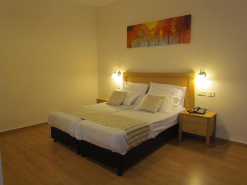 a bedroom with a large bed and a night stand at Berger Hotel in Tiberias