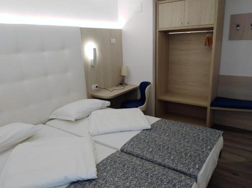 two beds in a room with a desk and a table at Hotel Orchidea in Bardolino