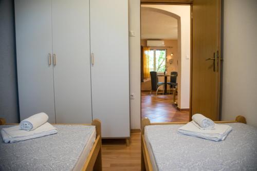 ein Schlafzimmer mit 2 Betten und einen Flur mit einem Spiegel in der Unterkunft Apartmani M&C in Fažana