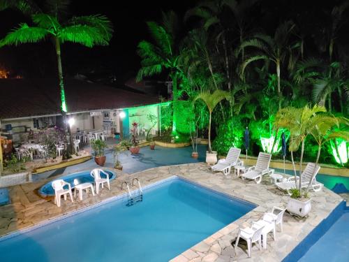 a swimming pool at night with white chairs and a resort at Apartamentos Atobá Flats in Juquei