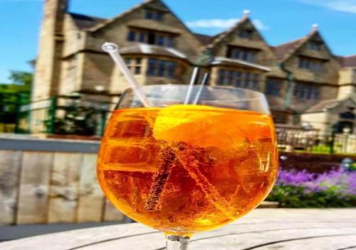 a drink in a glass on a table in front of a house at Weston Hall in Stafford