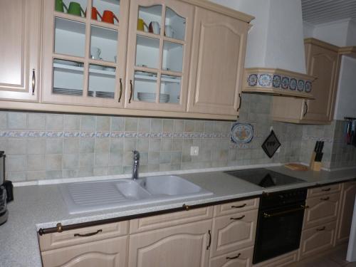 uma cozinha com armários brancos e um lavatório em Ferienwohnung Lorenzen em Husum