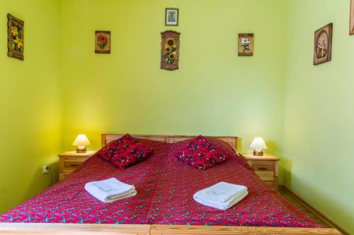 a bedroom with a bed with red sheets and pillows at TatryTop Apartamenty Zaciszne in Zakopane