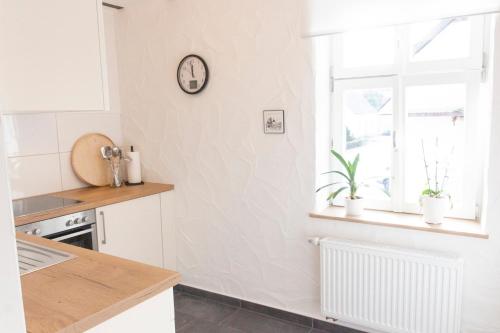 a kitchen with a window and a clock on the wall at Ferienwohnungen Zur Tenne in Beckingen