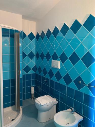a blue tiled bathroom with a toilet and a shower at Hotel La Ciaccia in Valledoria