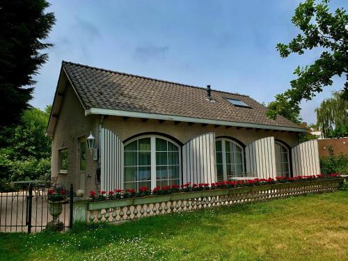 a small house with a fence and red flowers at Hotel Pension 't Huys Grol in Renesse