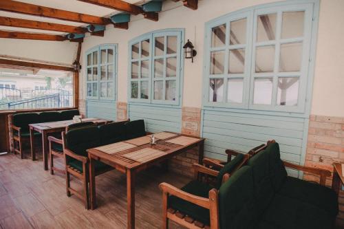 a restaurant with tables and chairs and windows at Ötösfogat Panzió in Siófok