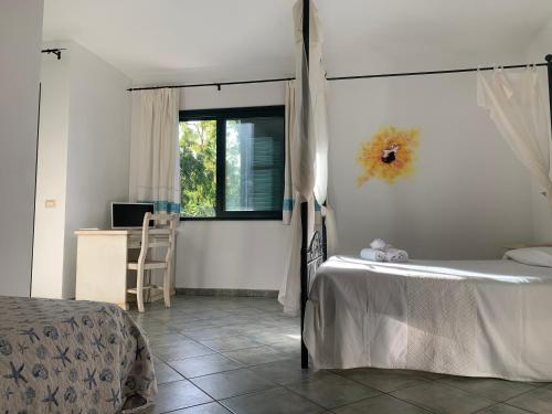 1 dormitorio con cama, ventana y escritorio en Hotel La Ciaccia, en Valledoria