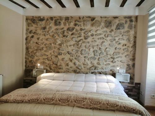 1 dormitorio con 1 cama grande y pared de piedra en Habitacion tienda de felipe EL DESPACHO, en Pontones