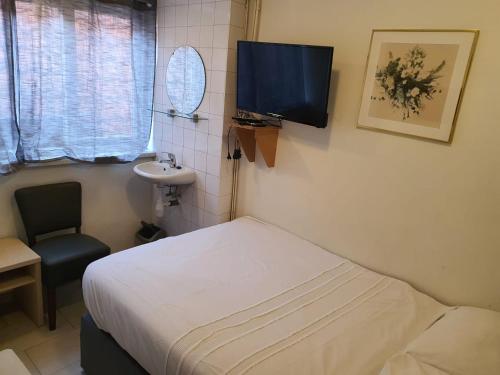 um pequeno quarto com uma cama e um lavatório em Hotel Schroder em Amesterdão