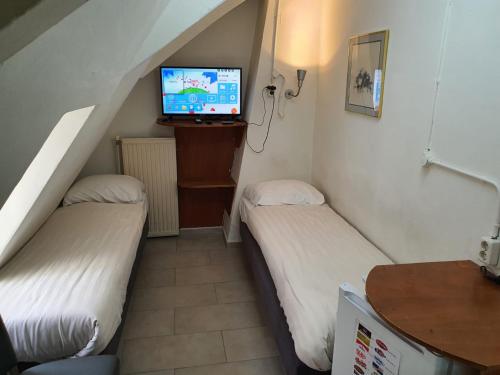 two beds in a room with a tv on the wall at Hotel Schroder in Amsterdam