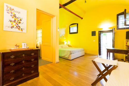 a yellow bedroom with a bed and a dresser in it at B&B Corte delle Muse in San Felice del Benaco