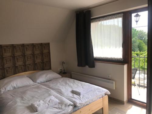 a bedroom with a bed and a large window at Berger Pince és vendégház in Császártöltés