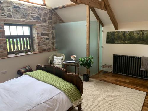 a bedroom with a bed and a stone wall at The Granary in Lifton
