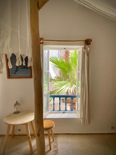 a window in a room with a table and a chair at Riad Baladin in Essaouira