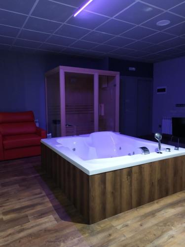 a large bath tub in a room with a red couch at Motel Los Abedules in Oviedo