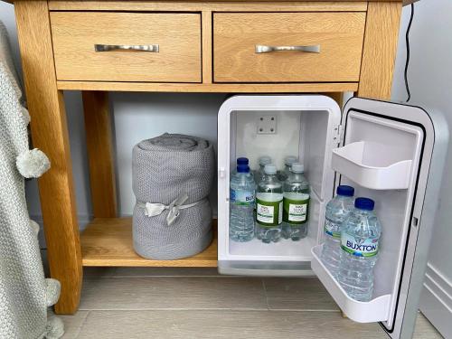 um frigorífico aberto com garrafas de água e um saco em Maugersbury Park Suite em Stow on the Wold