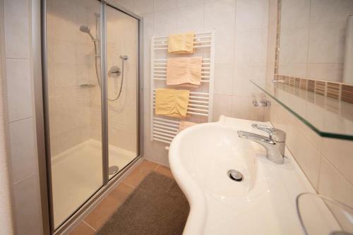 a white bathroom with a shower and a sink at Haus Sonnwend in Sölden