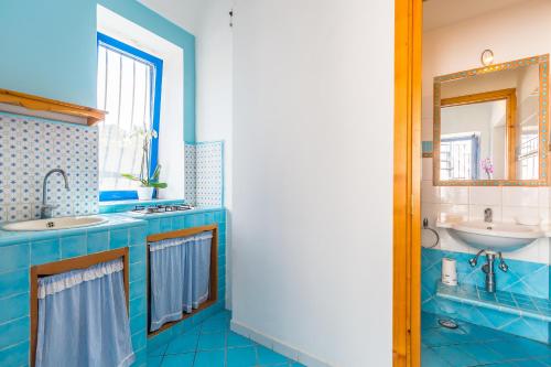 La salle de bains bleue est pourvue d'un lavabo et d'un miroir. dans l'établissement La finestra sul mare, à Procida
