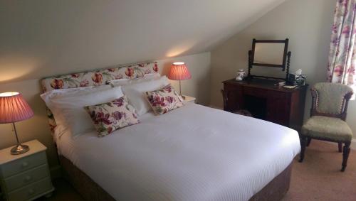 a bed room with a white bedspread and pillows at Lochinver Guesthouse in Ayr