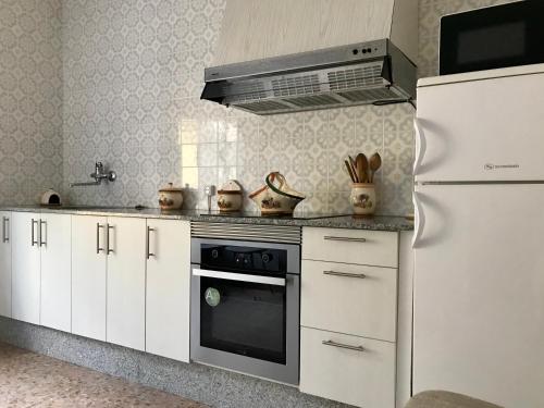 uma cozinha com armários brancos e um forno com placa de fogão em Casa de la Abuela em Fabero