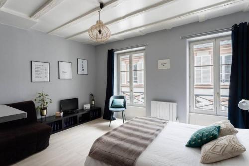 une chambre avec un lit, une chaise et des fenêtres dans l'établissement R-Appartements Strasbourg La Petite Strasbourgeoise Hygge studio cosy, à Strasbourg