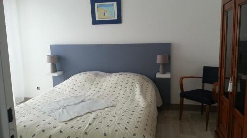 um quarto com uma cama branca e uma parede azul em Les Trinitaires em Sarzeau