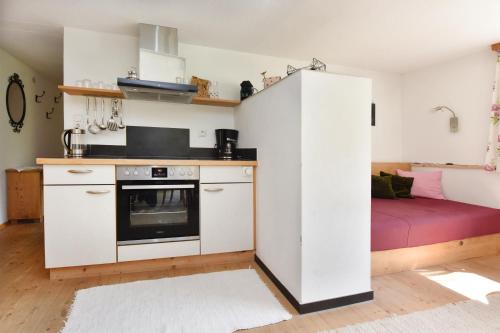 a kitchen with white cabinets and a red couch at Familienbauernhof Köss Schertler in Egg