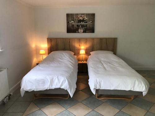 two beds in a room with white sheets and lights at Schirnaublick in Bünsdorf