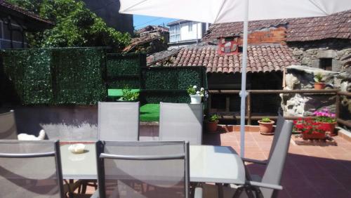 a patio with a table and chairs and an umbrella at Casa en el rural de Galicia, A Forneira in Leiro