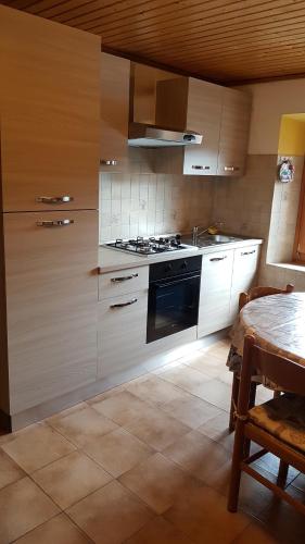 cocina con armarios blancos, fogones y mesa en Appartamento Comelico Dolomiti, en Candide