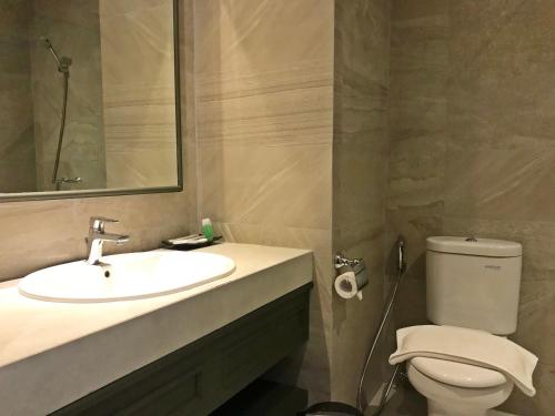 ein Badezimmer mit einem Waschbecken, einem WC und einem Spiegel in der Unterkunft Hotel Shalva Jakarta in Jakarta