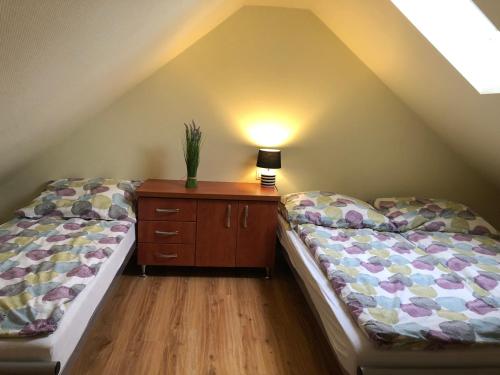 a attic room with two beds and a wooden dresser at Domki DRAGON Łeba in Łeba
